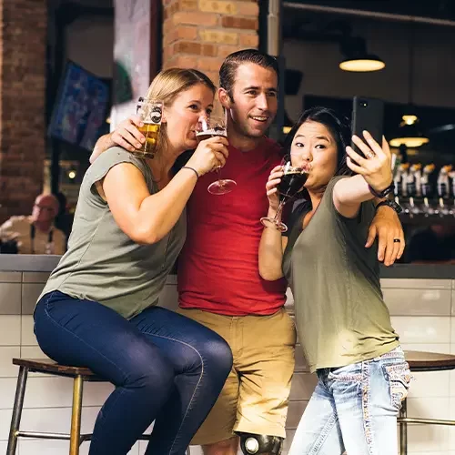 A Man in red T-Shirt and two girls enjoying beer